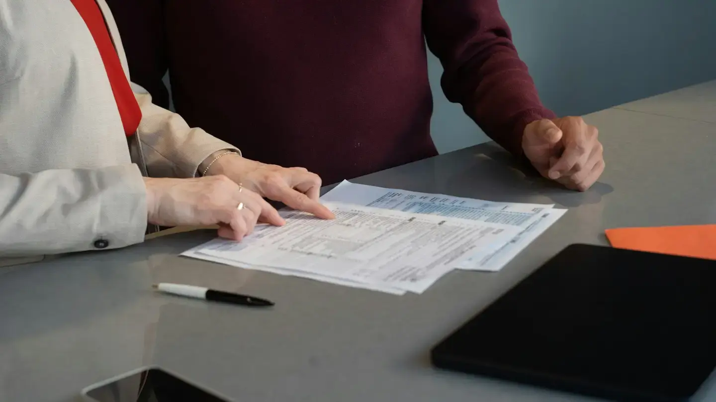 Deux personnes relisent ensemble un formulaire réglementaire posé sur une table