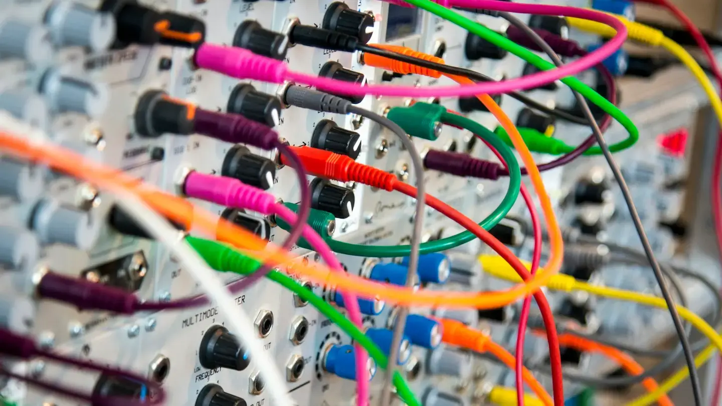 Enchevêtrement de câbles colorés branchés sur un panneau de connexions