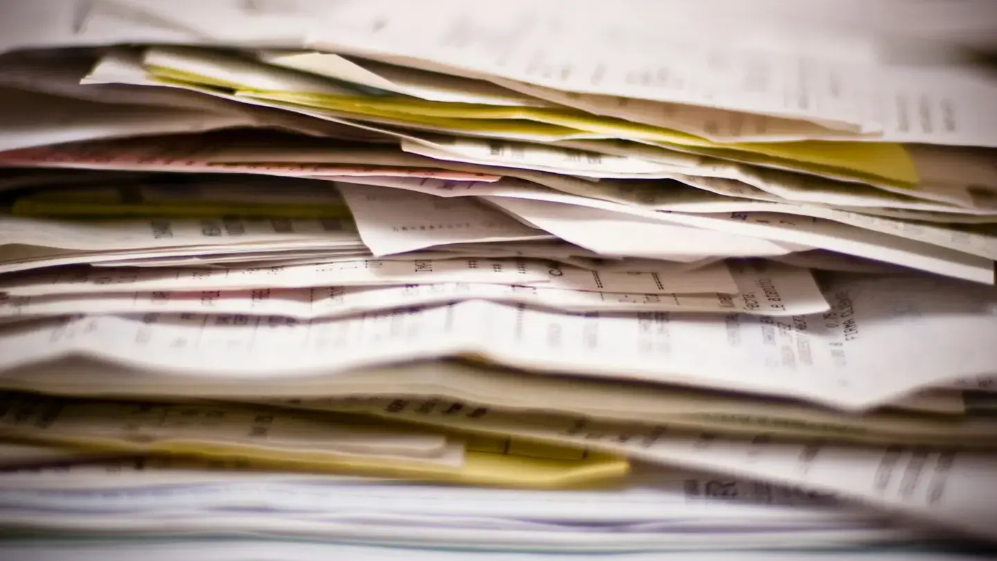 Pile de factures papier et de bordereaux empilés sur un bureau
