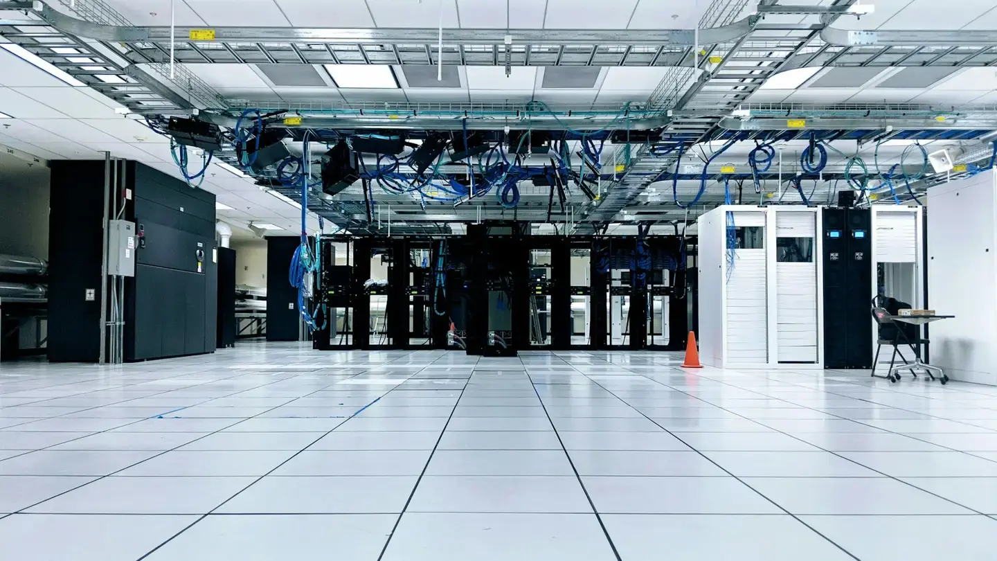 Salle serveur lumineuse avec des baies informatiques et des chemins de câbles bleus au plafond