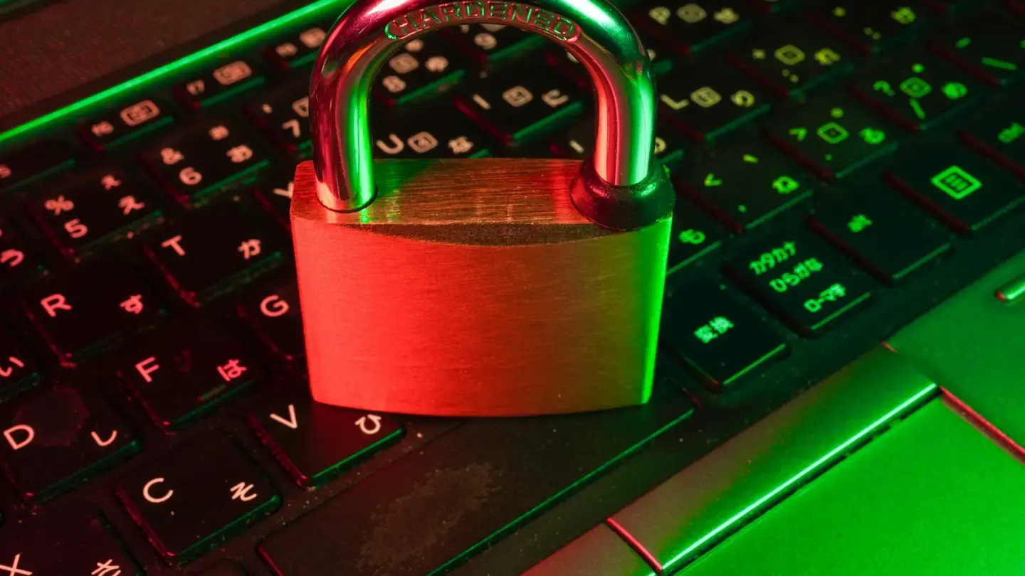Cadenas métallique posé sur un clavier d’ordinateur rétroéclairé en rouge et vert