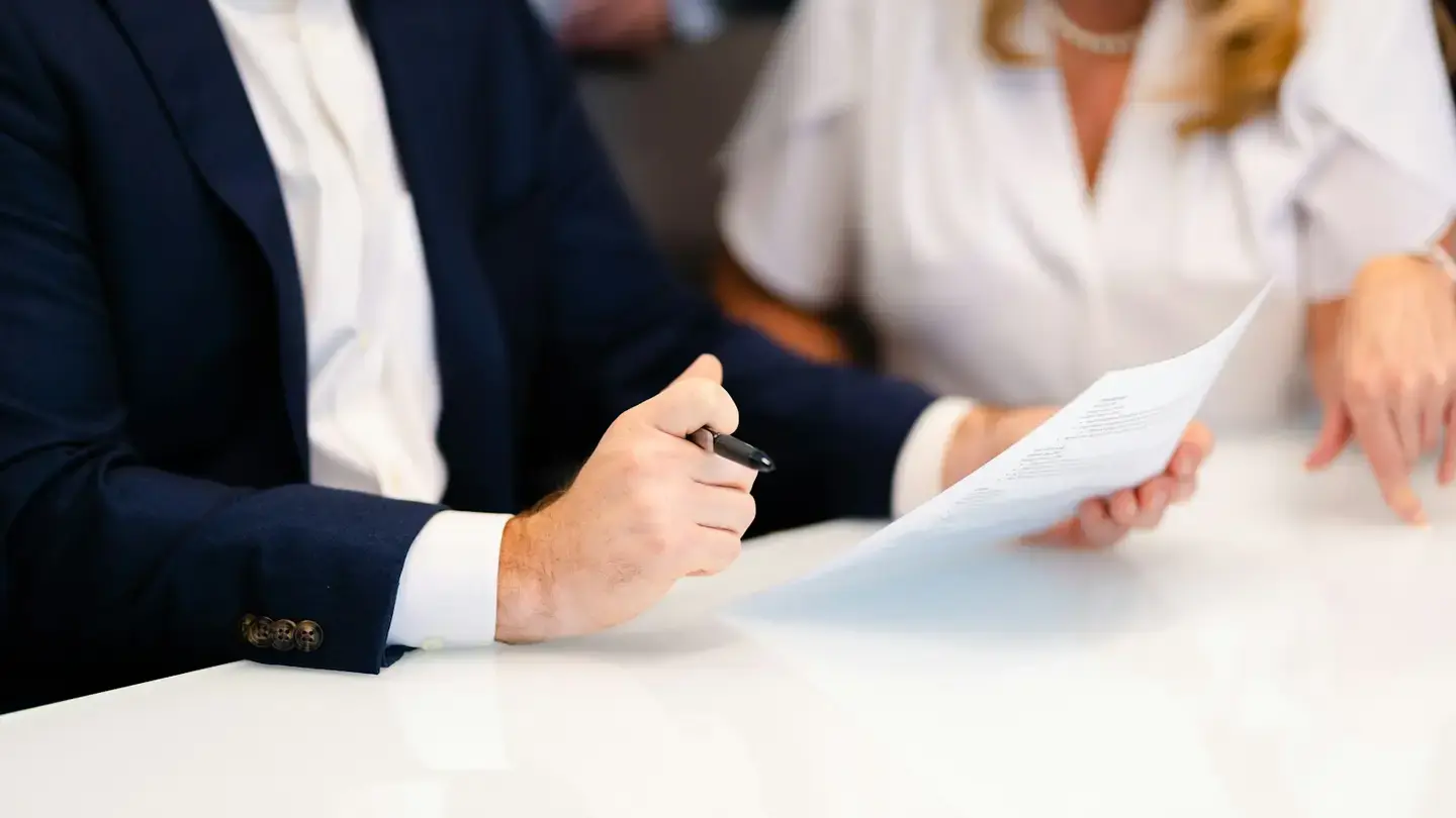 Un responsable stylo en main examine un document que lui présente une collaboratrice