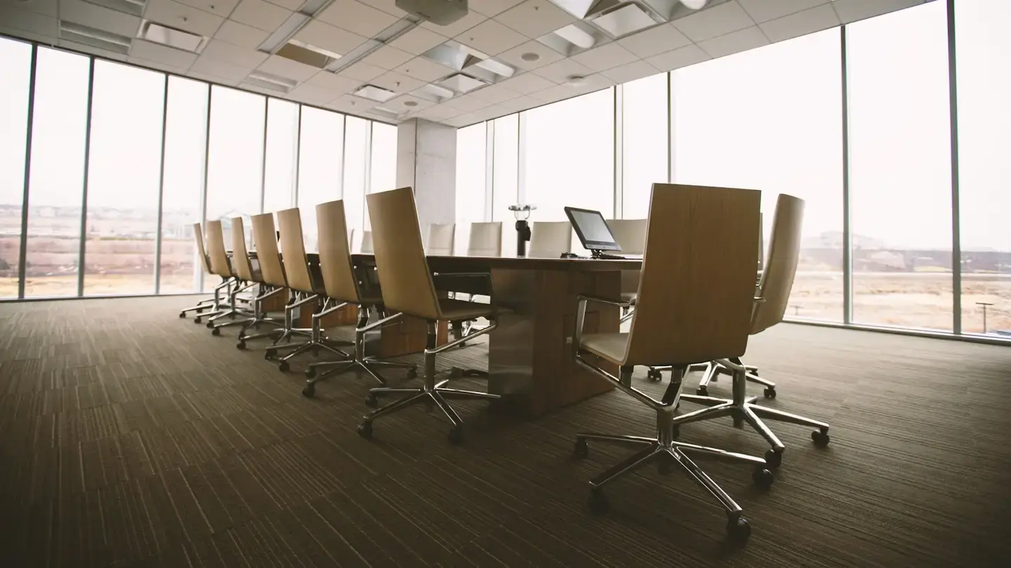 Salle de réunion vide avec une longue table, des fauteuils et de grandes baies vitrées