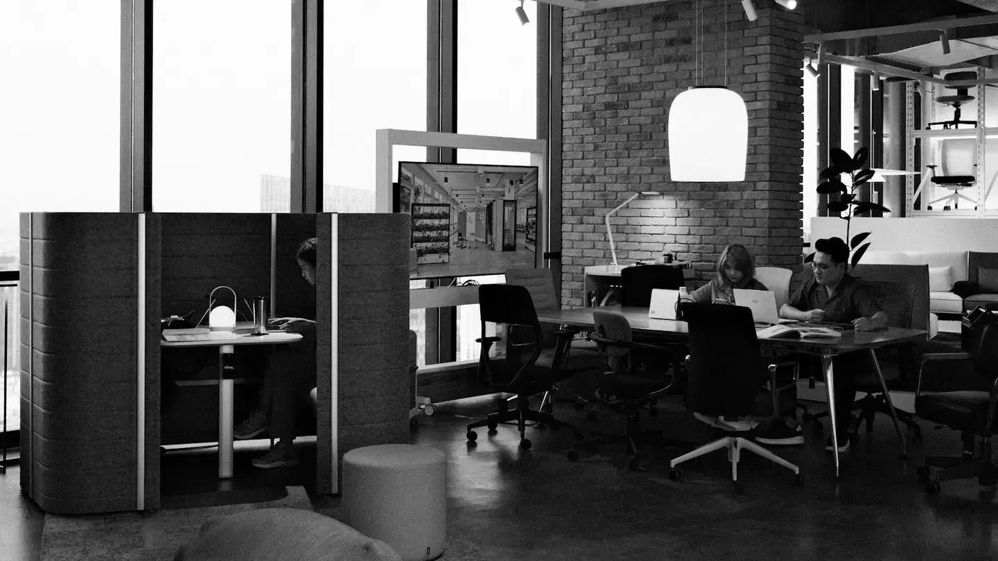 Plateau de bureaux moderne en noir et blanc, collaborateurs au travail sur ordinateurs portables