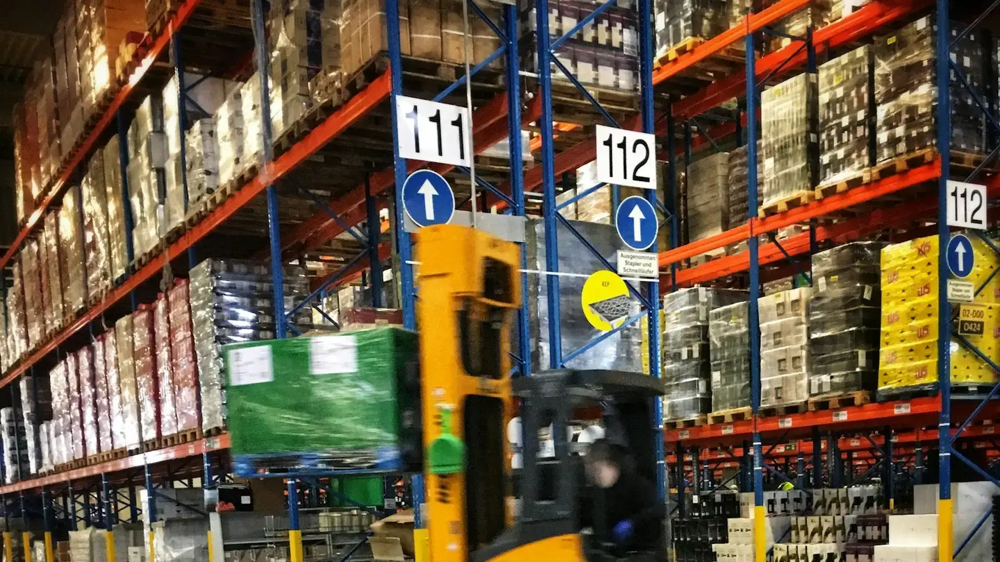 Chariot élévateur circulant entre des racks de palettes filmées dans un entrepôt de distribution