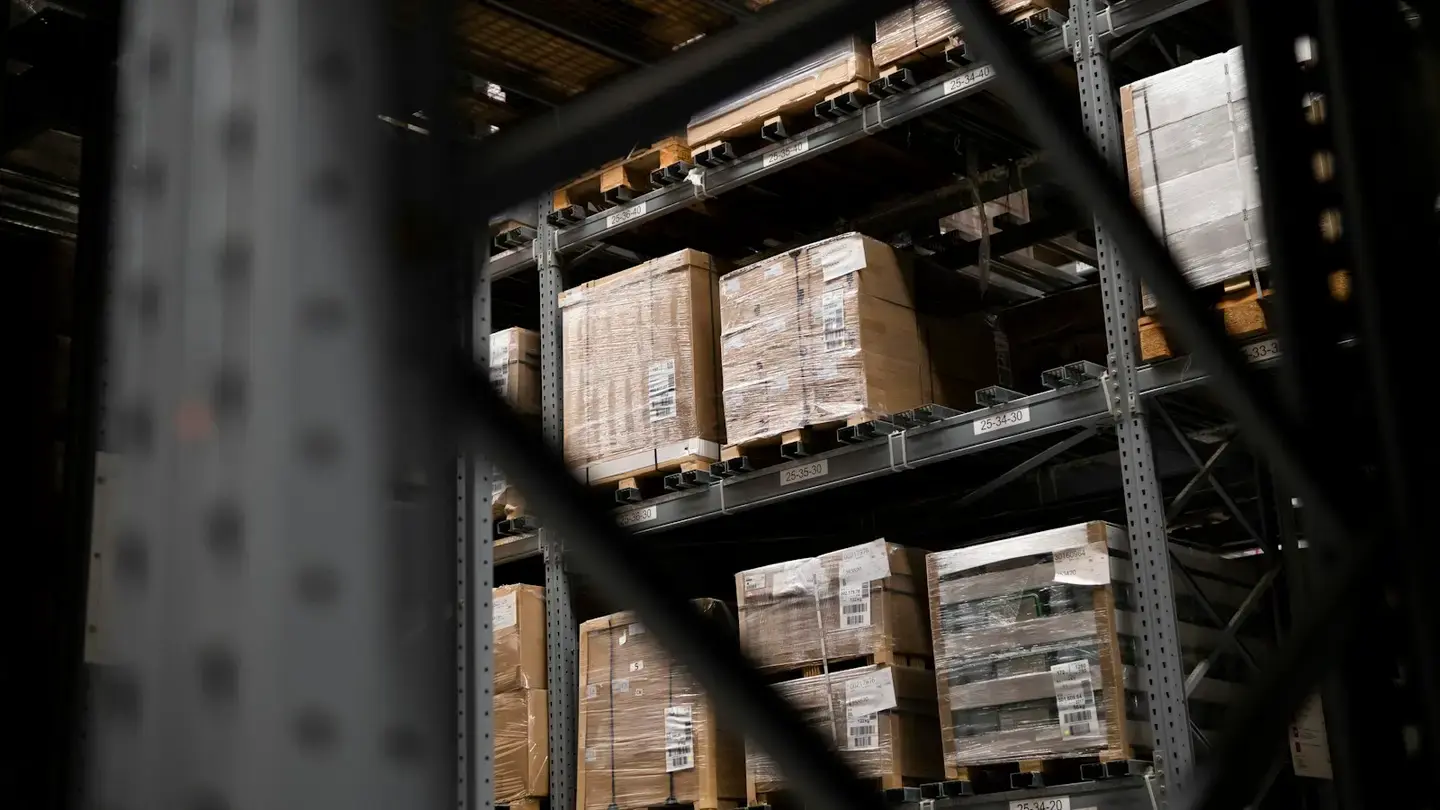 Palettes filmées et étiquetées rangées sur des racks dans un entrepôt