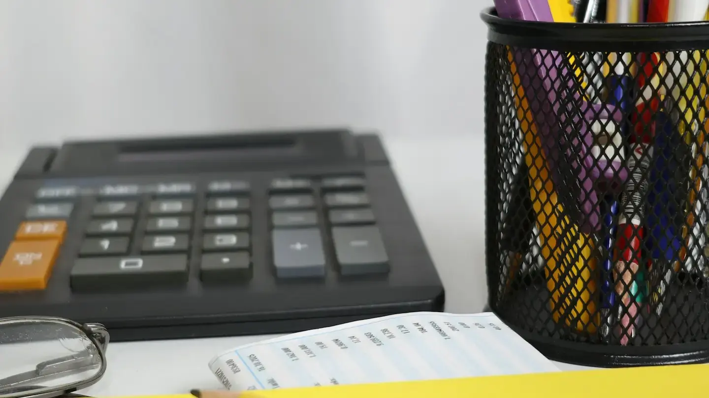 Calculatrice de bureau, ticket imprimé et pot à crayons sur un bureau clair