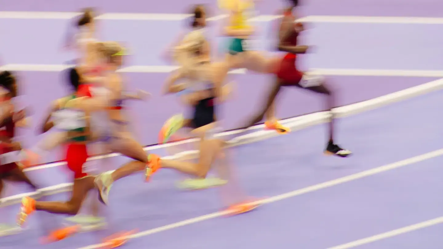 Coureuses en pleine course sur une piste d’athlétisme, image floutée par la vitesse