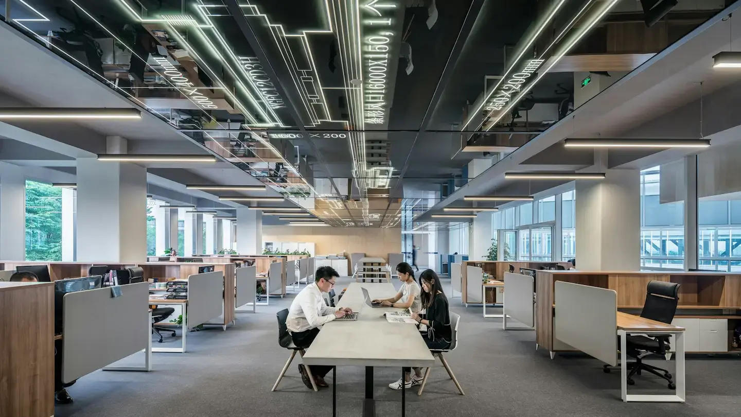 Plateau de bureaux ouvert et lumineux où trois collaborateurs travaillent sur une grande table centrale
