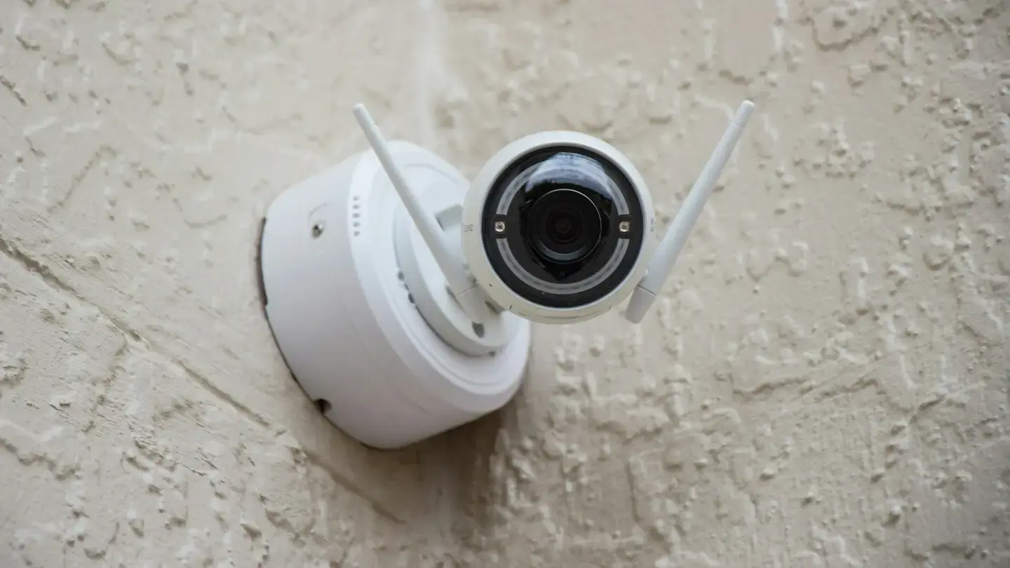 Caméra de surveillance blanche fixée sur un mur crépi