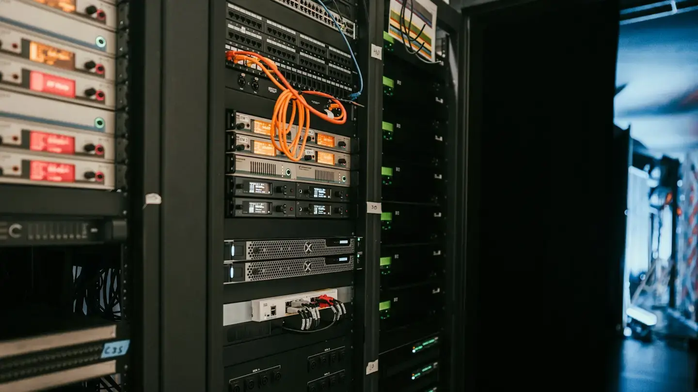 Baie de serveurs et d’équipements réseau avec câbles orange dans une salle technique