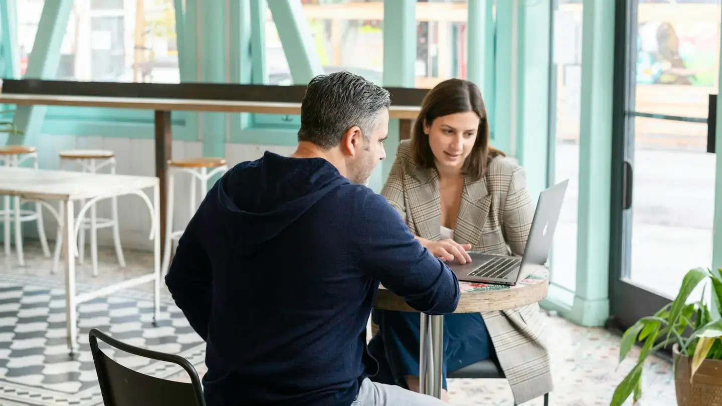 Deux professionnels échangent autour d’un ordinateur portable à une table