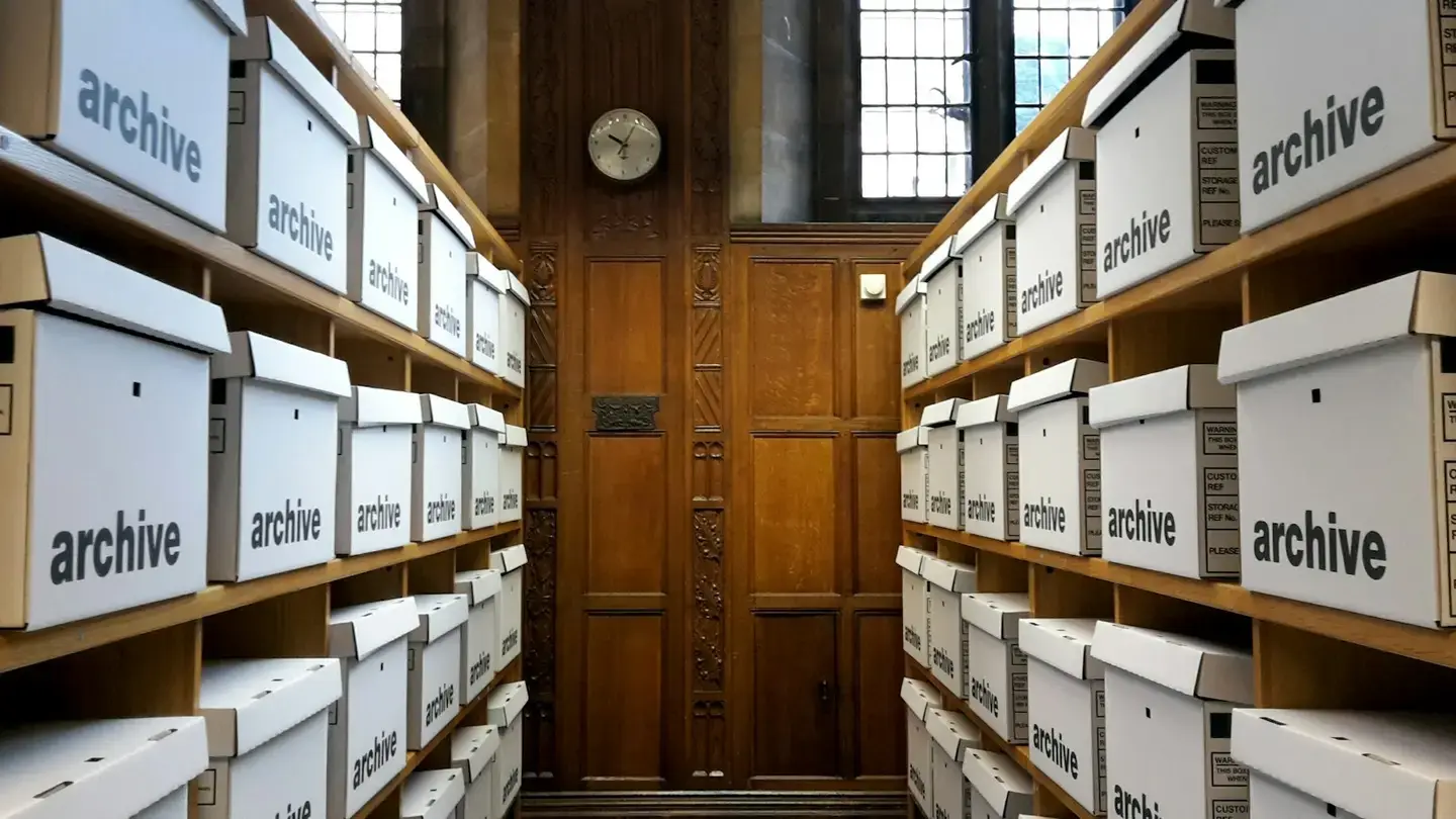 Allée d’archives aux étagères remplies de boîtes blanches identiques