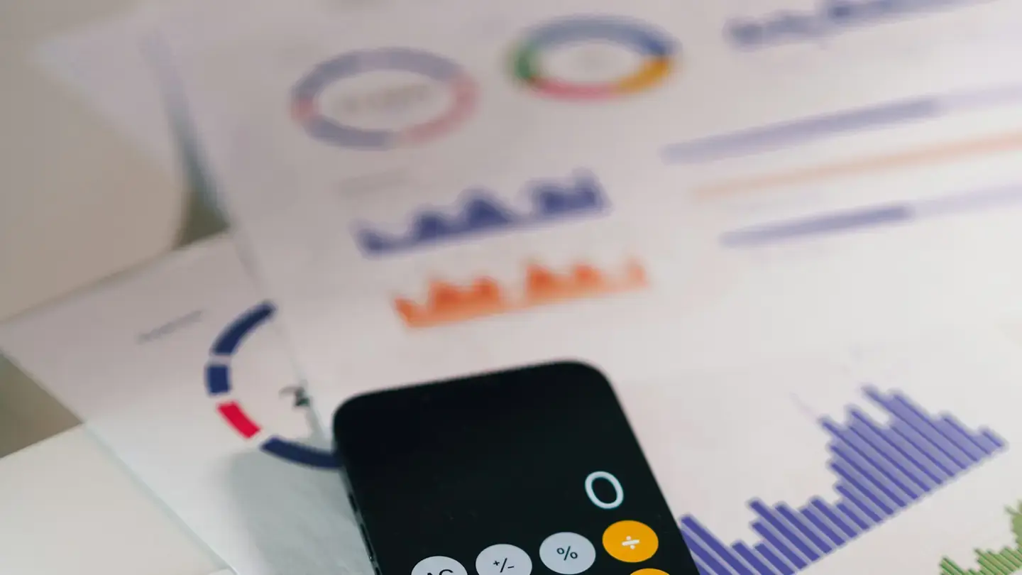 Smartphone affichant une calculatrice posé sur des rapports imprimés avec des graphiques