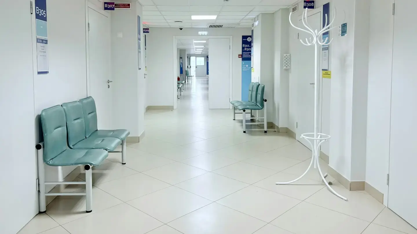 Couloir d’un établissement de soins avec des sièges d’attente et des portes de consultation numérotées