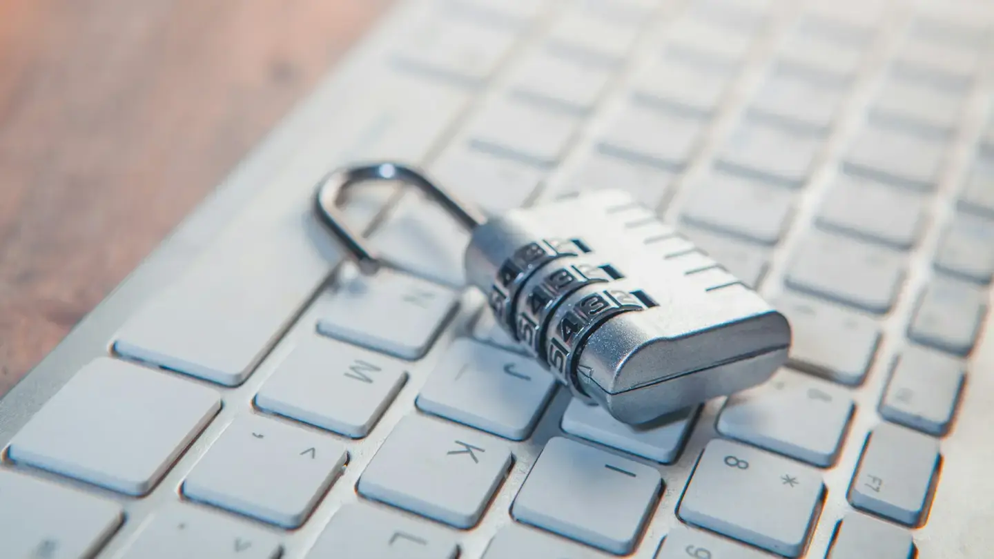 Cadenas à combinaison ouvert posé sur un clavier d’ordinateur clair