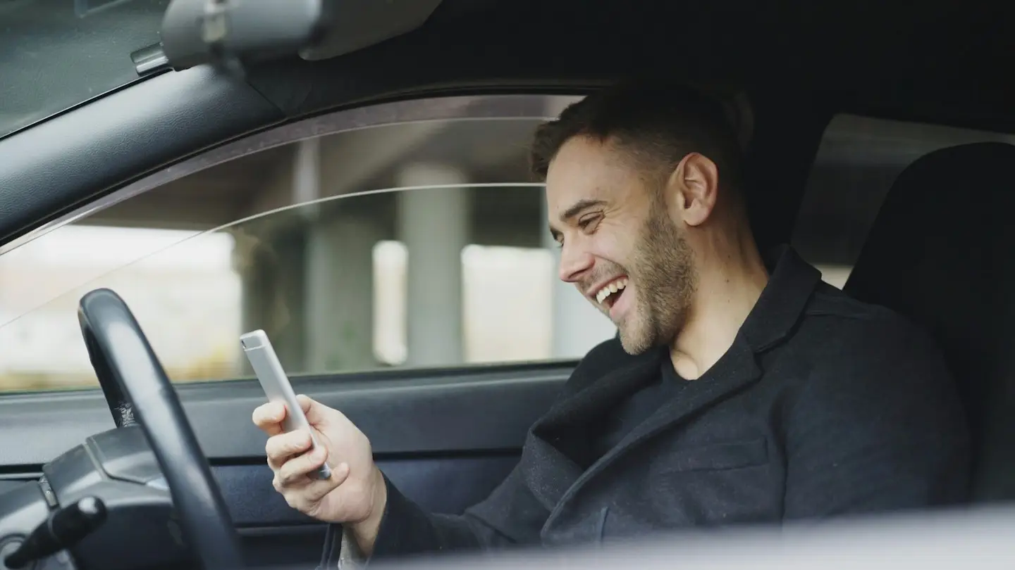 Un commercial assis dans sa voiture consulte son téléphone entre deux rendez-vous