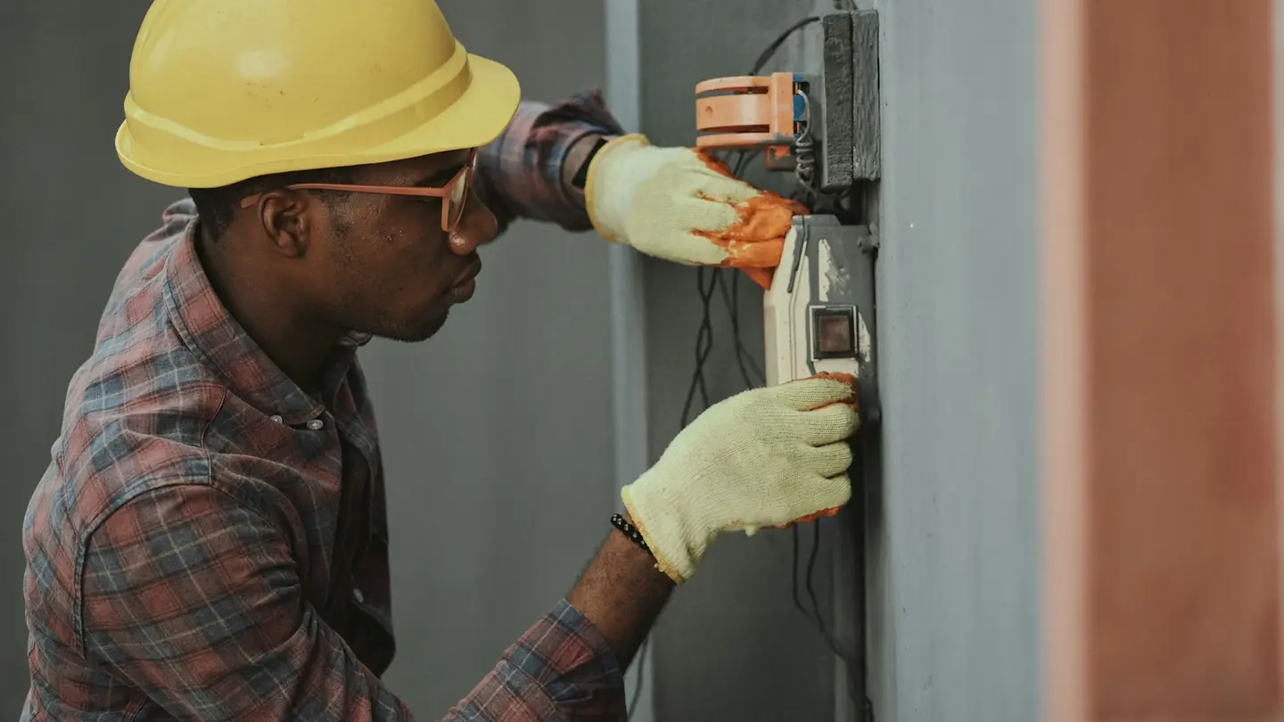 Électricien en casque de chantier travaillant sur un boîtier électrique mural