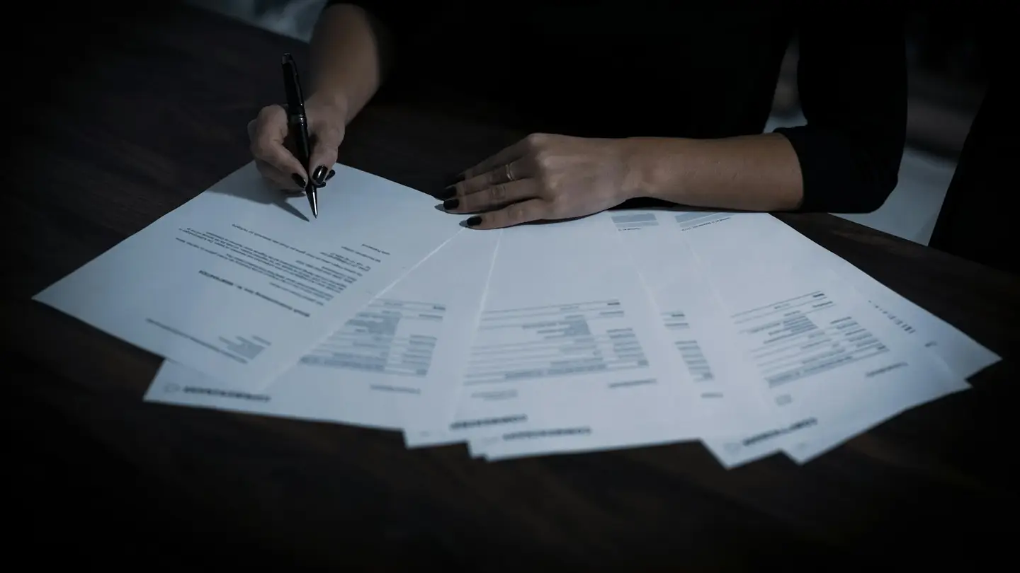 Une personne annote une série de formulaires papier étalés sur une table