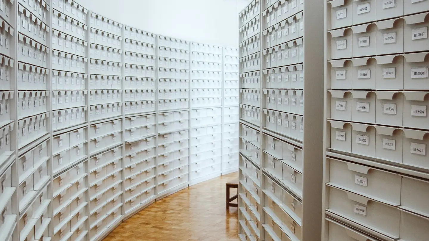 Couloir bordé de casiers d’archives blancs numérotés et soigneusement rangés