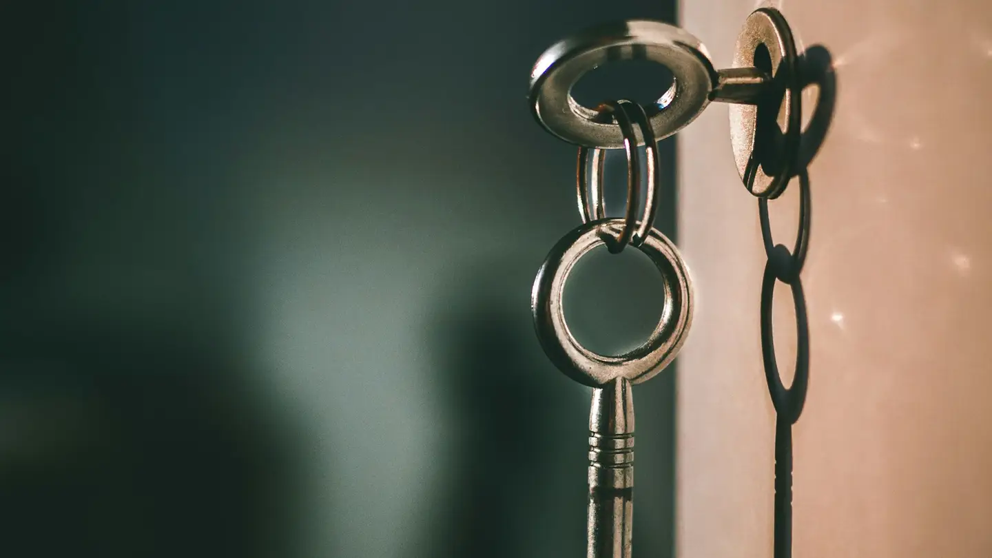 Clé ancienne engagée dans une serrure, éclairée par une lumière rasante