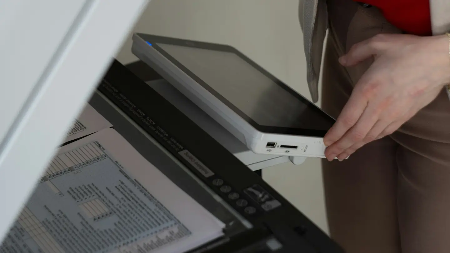 Une personne dépose un document dans un copieur-scanner de bureau