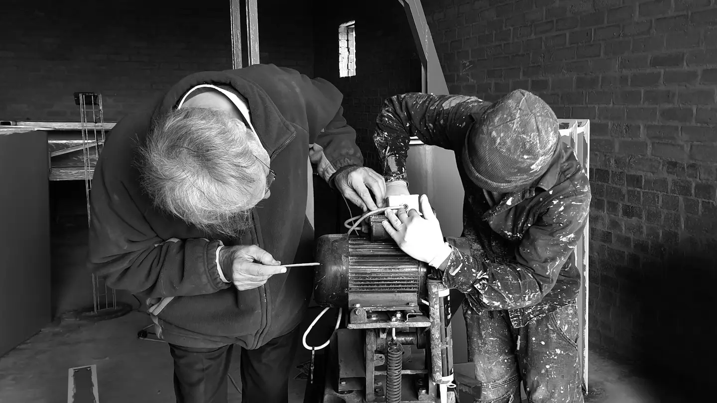 Deux techniciens réparent un moteur électrique dans un atelier, photo en noir et blanc