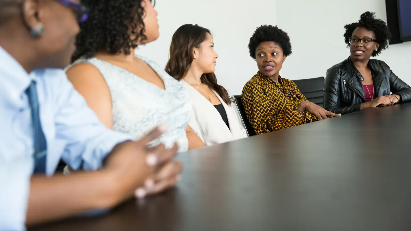 Cinq personnes échangent autour d’une table de réunion
