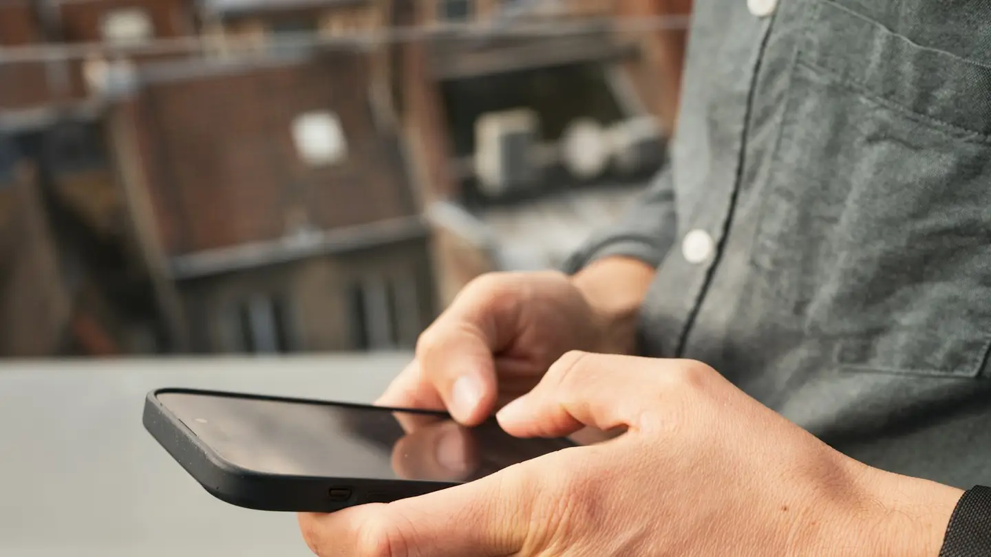 Gros plan sur les mains d’un collaborateur qui consulte son téléphone sur son lieu de travail