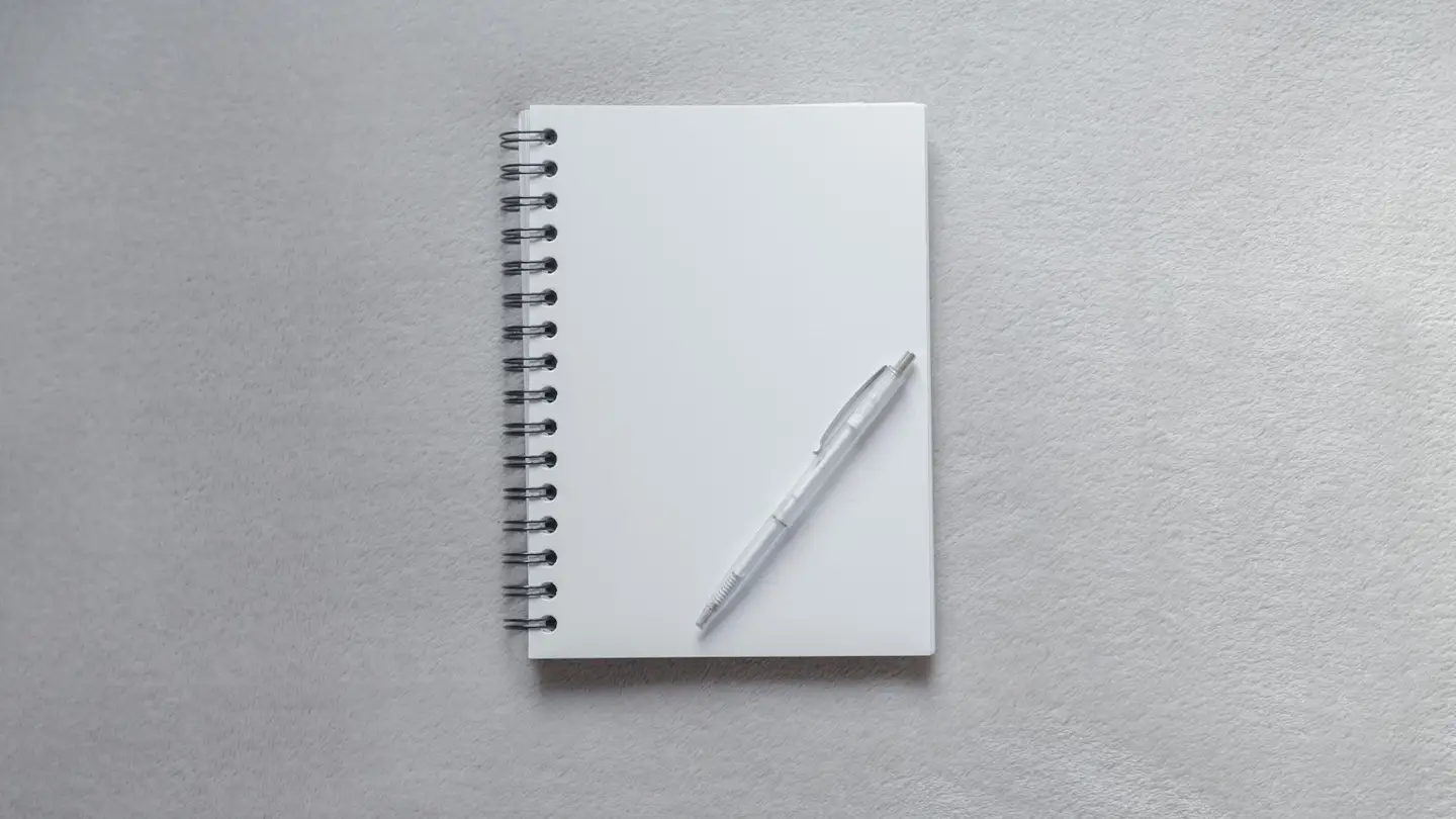 Carnet à spirale ouvert sur une page blanche, avec un stylo posé dessus
