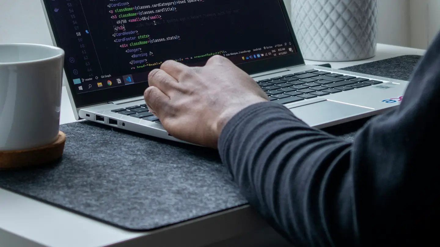 Développeur au travail sur un ordinateur portable affichant du code