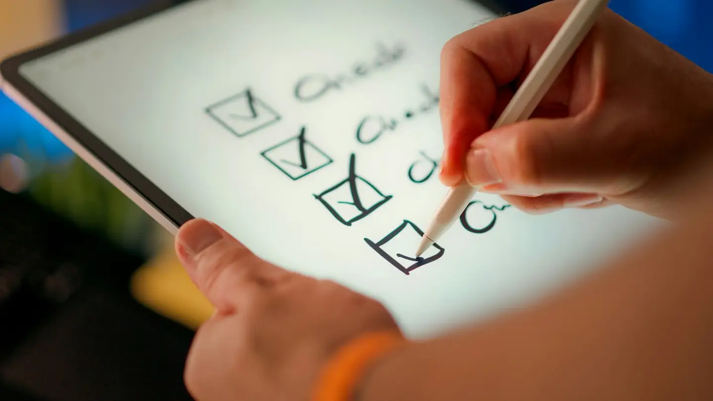 Main cochant une liste de contrôle sur une tablette avec un stylet