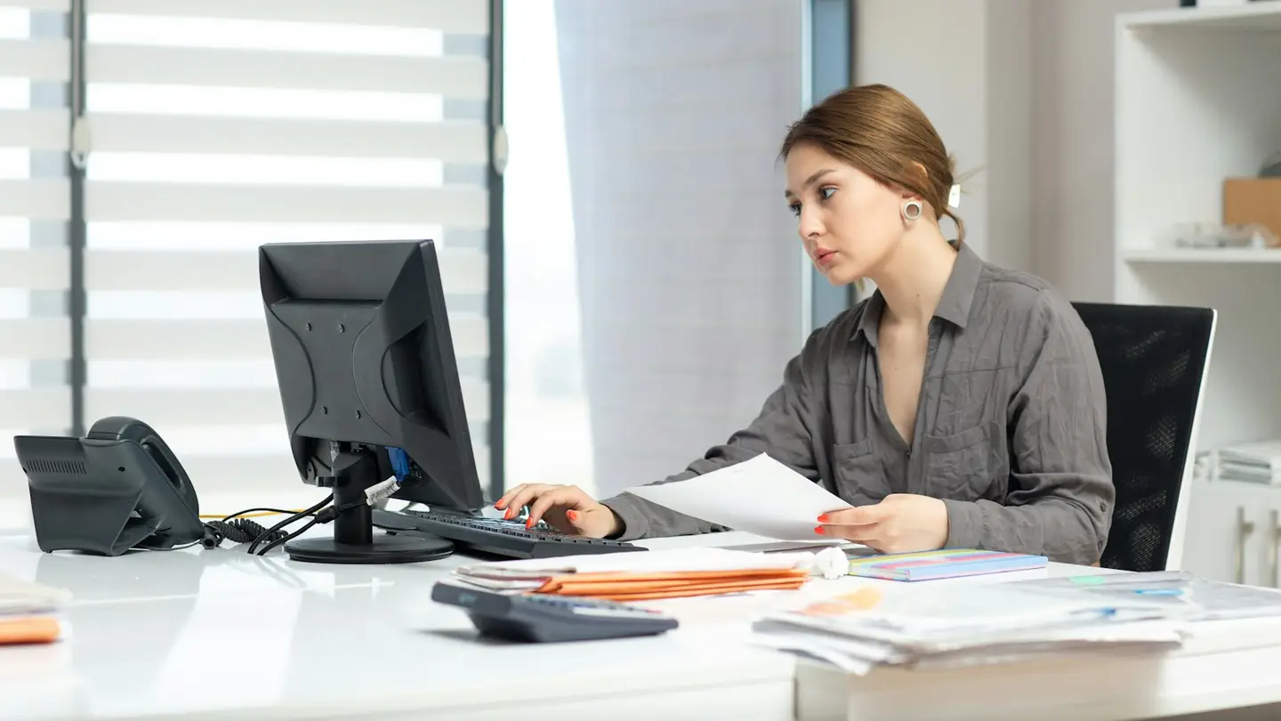 Une collaboratrice du service administratif vérifie des documents devant son écran