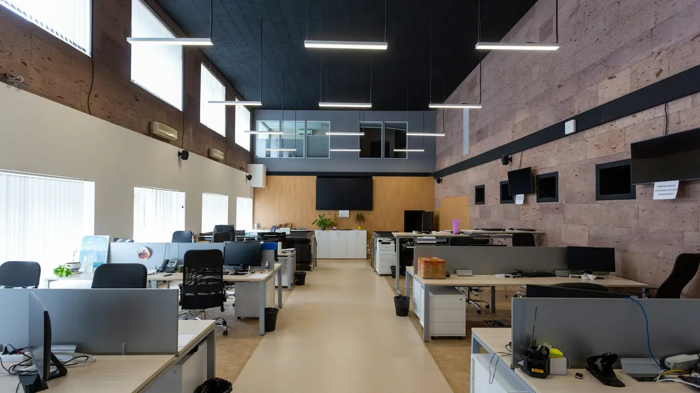 Grand plateau de bureaux vide avec des rangées de postes de travail et des écrans