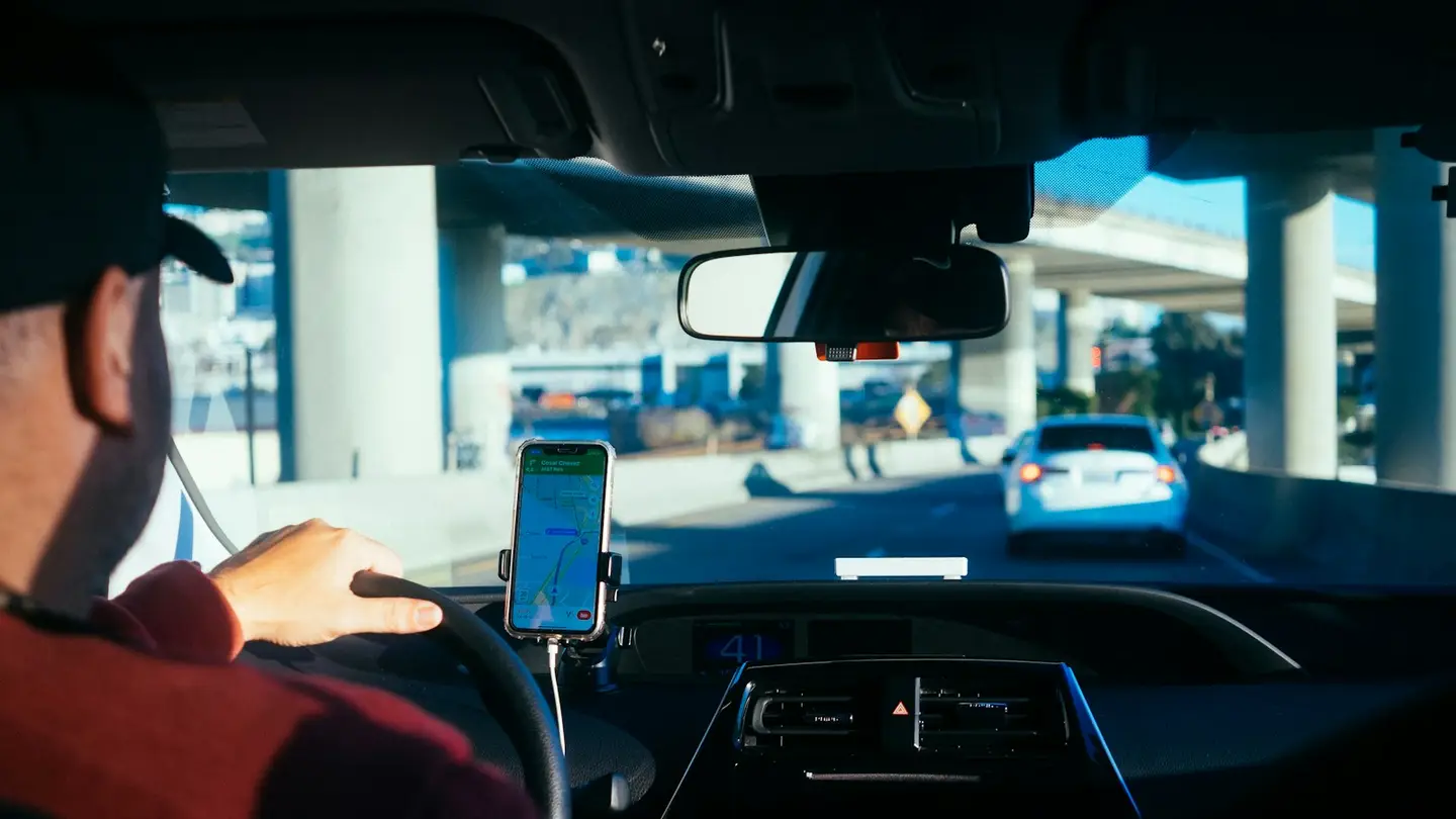Conducteur au volant, un smartphone fixé au tableau de bord affiche l’itinéraire